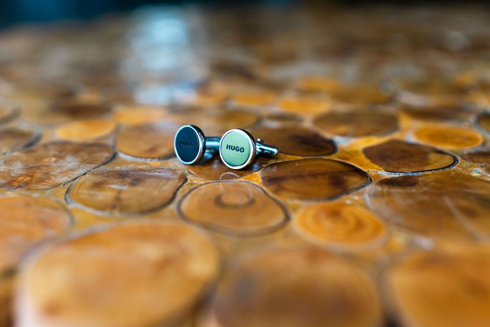 Wedding rings rest on a wooden honeycomb pattern surface with warm lighting.