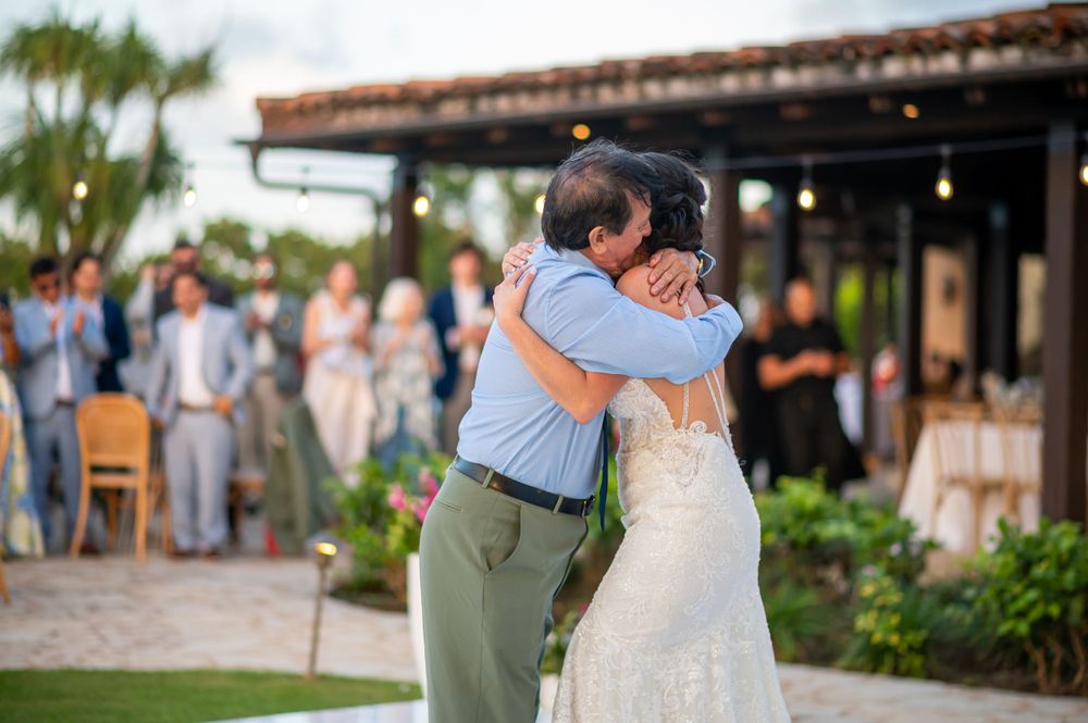 Couple embracing during romantic outdoor wedding dance at sunset.