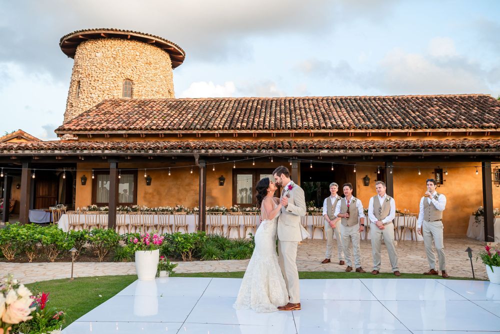Wedding ceremony in front of a rustic Mediterranean building with terra cotta roof and stone tower.