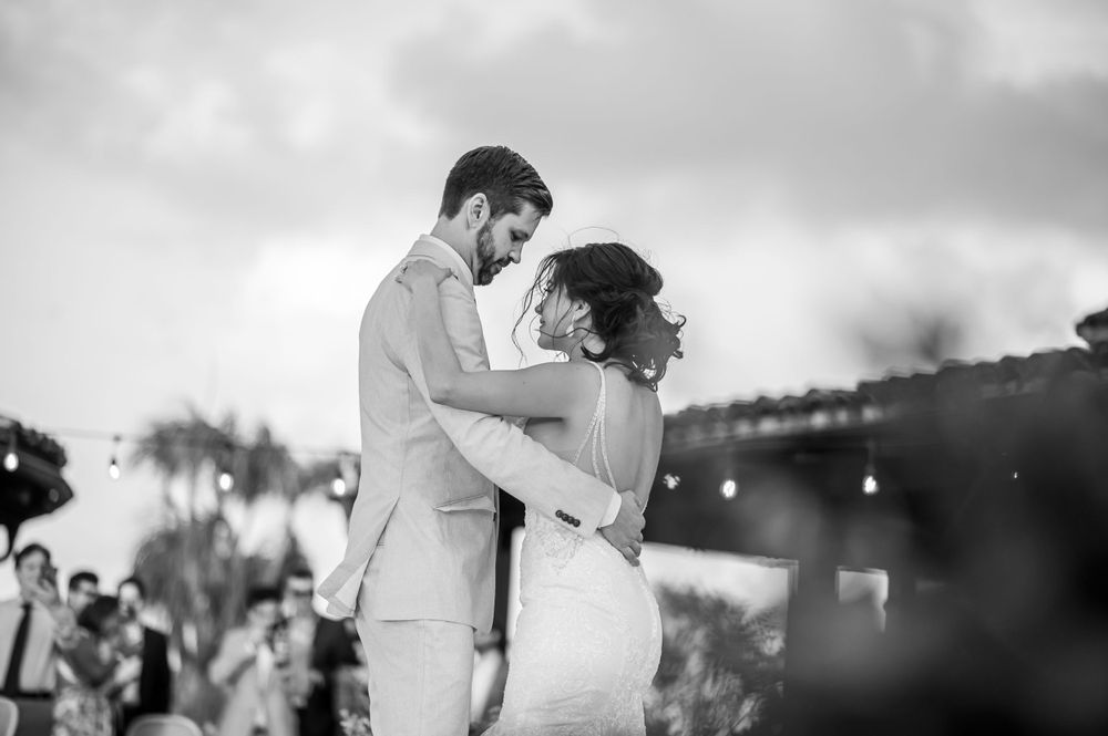Black and white intimate wedding dance moment captured against a dreamy evening sky.