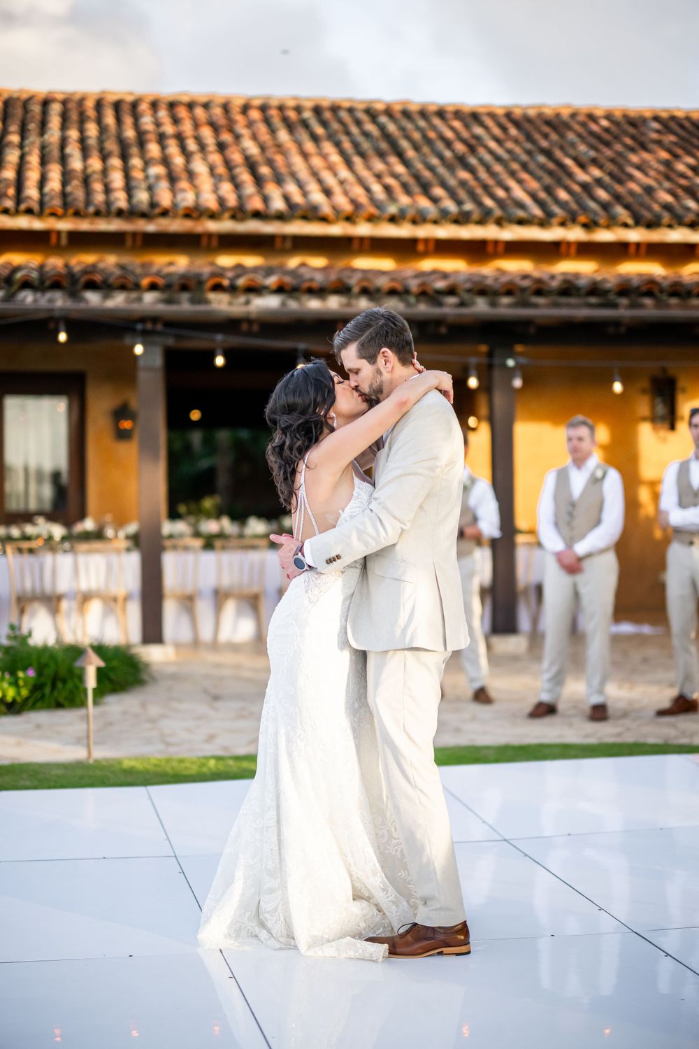First dance moment on a white dance floor with Spanish colonial architecture in the background.