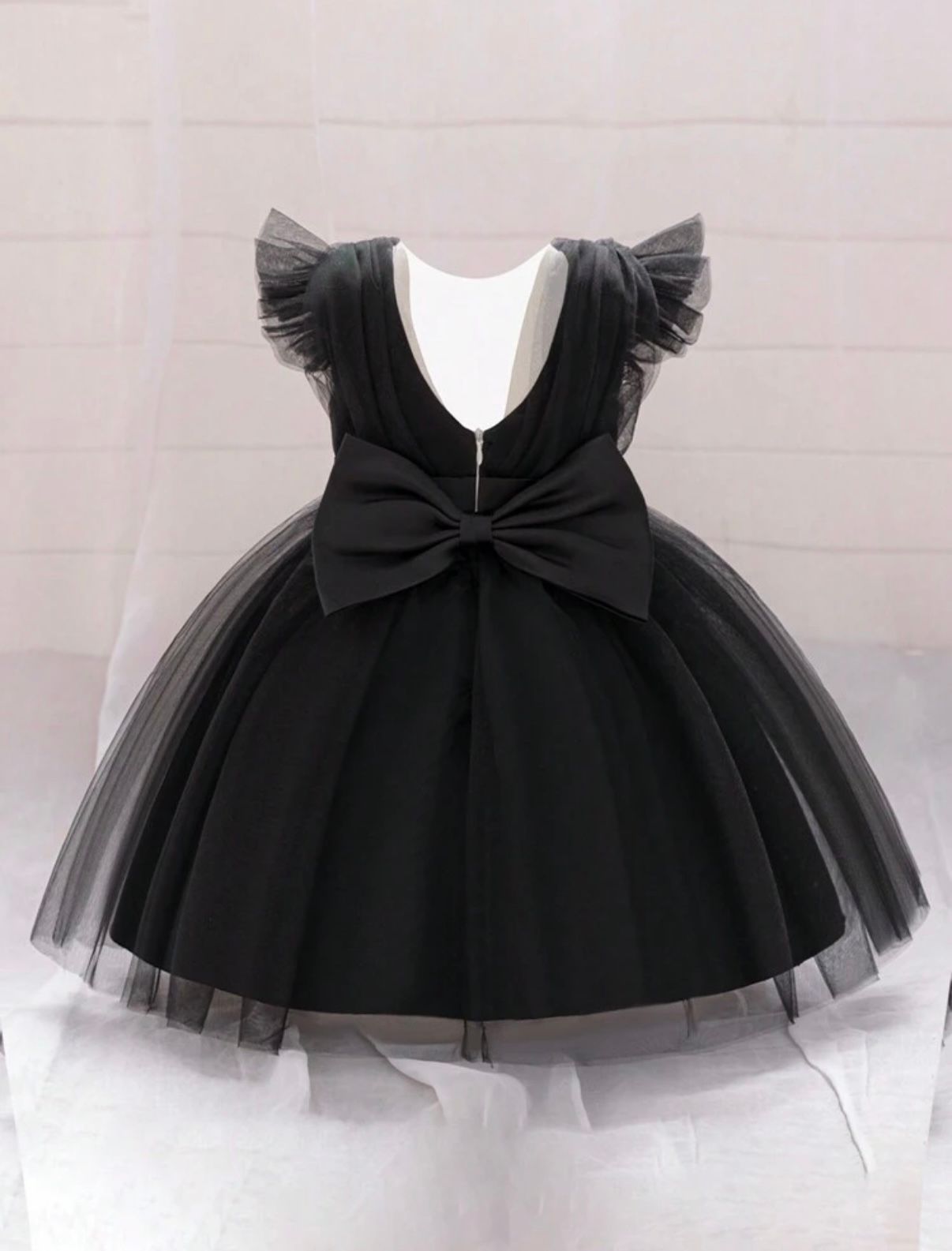Black tulle party dress with bow detail shown from different angles.