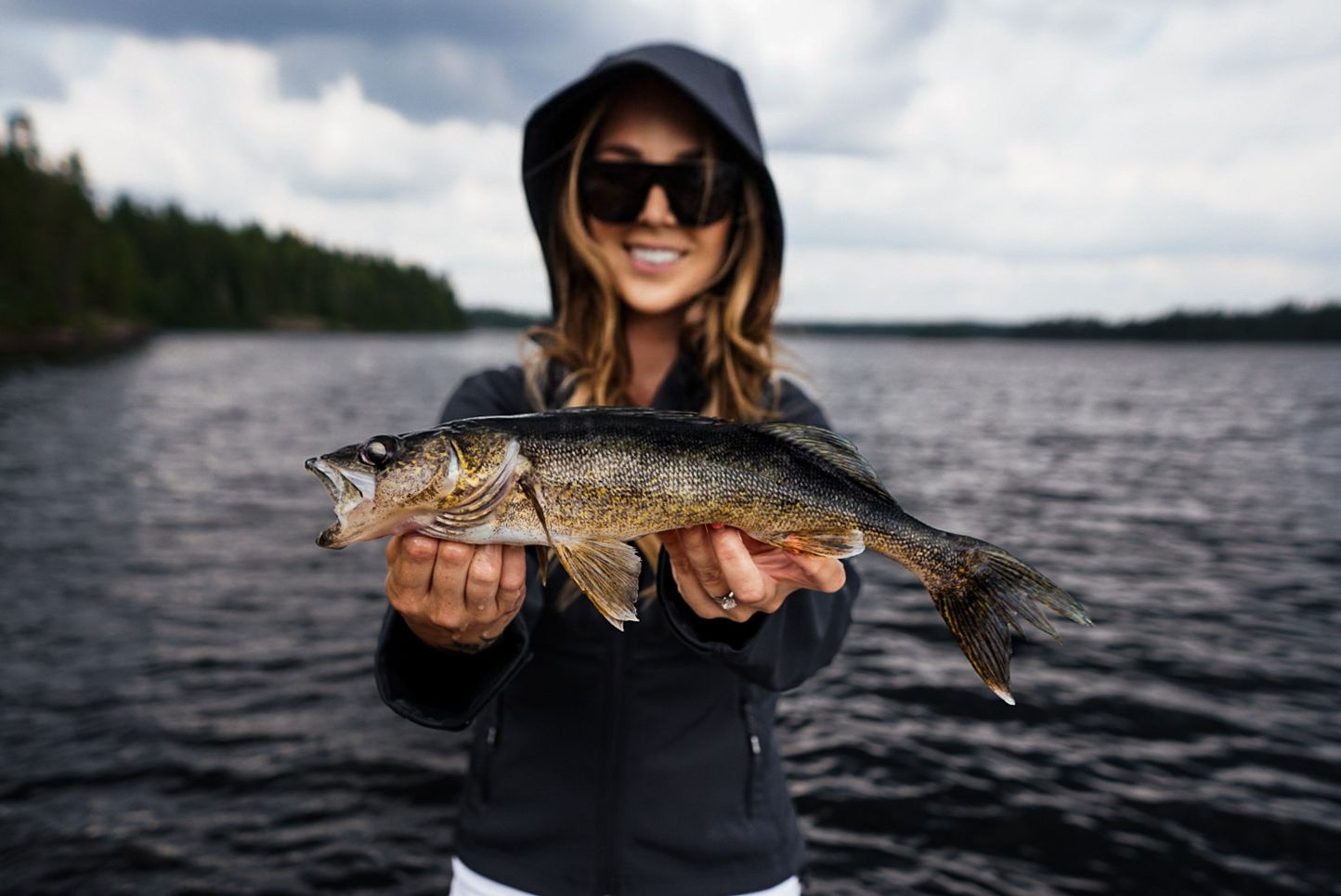Freshly caught northern pike displayed against dark waters of a lake.