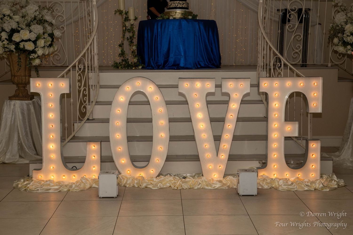 Illuminated LOVE marquee letters on display with blue backdrop and twinkling lights.