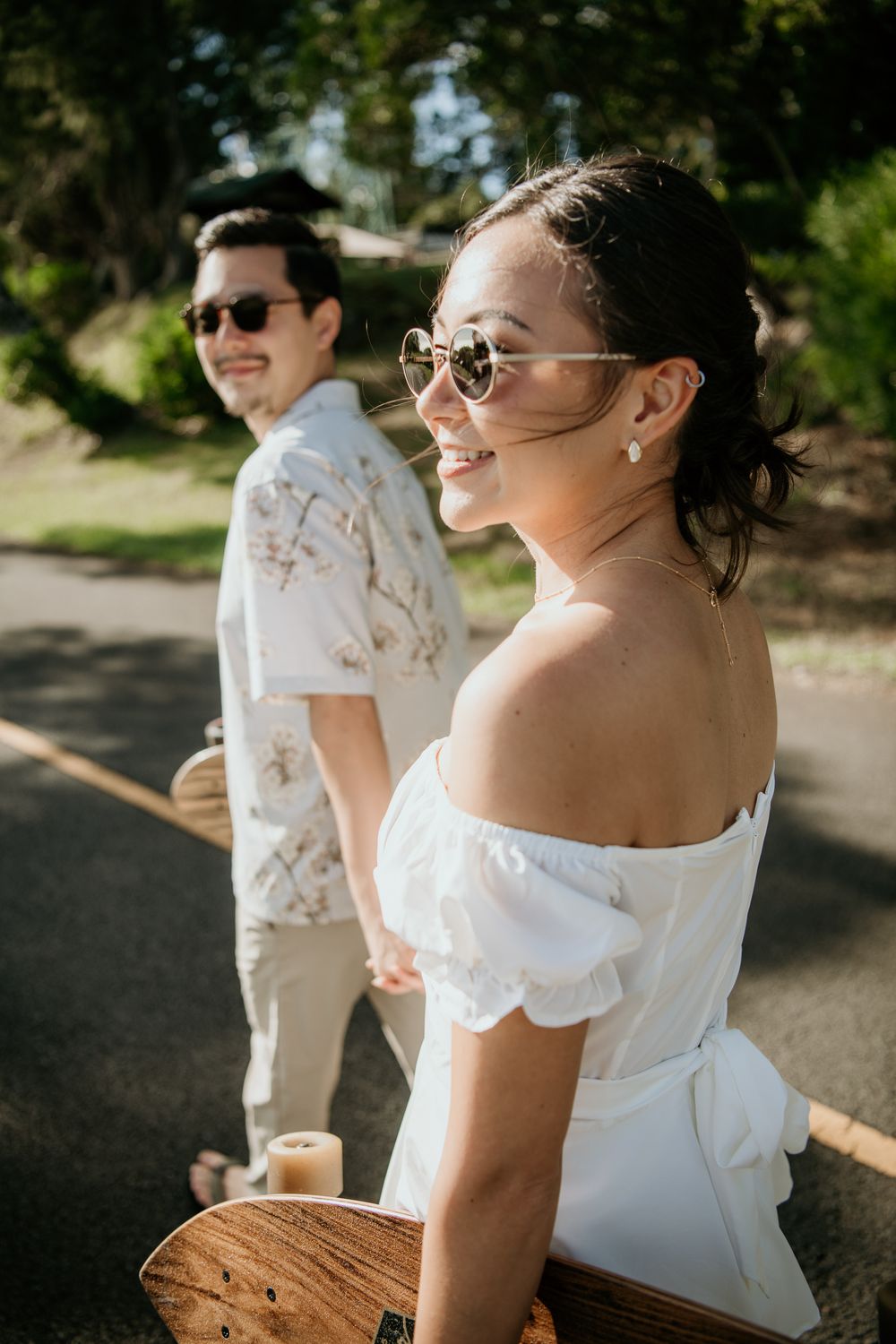 A couple in casual summer attire and sunglasses enjoying a sunny day outdoors with matching white outfits.