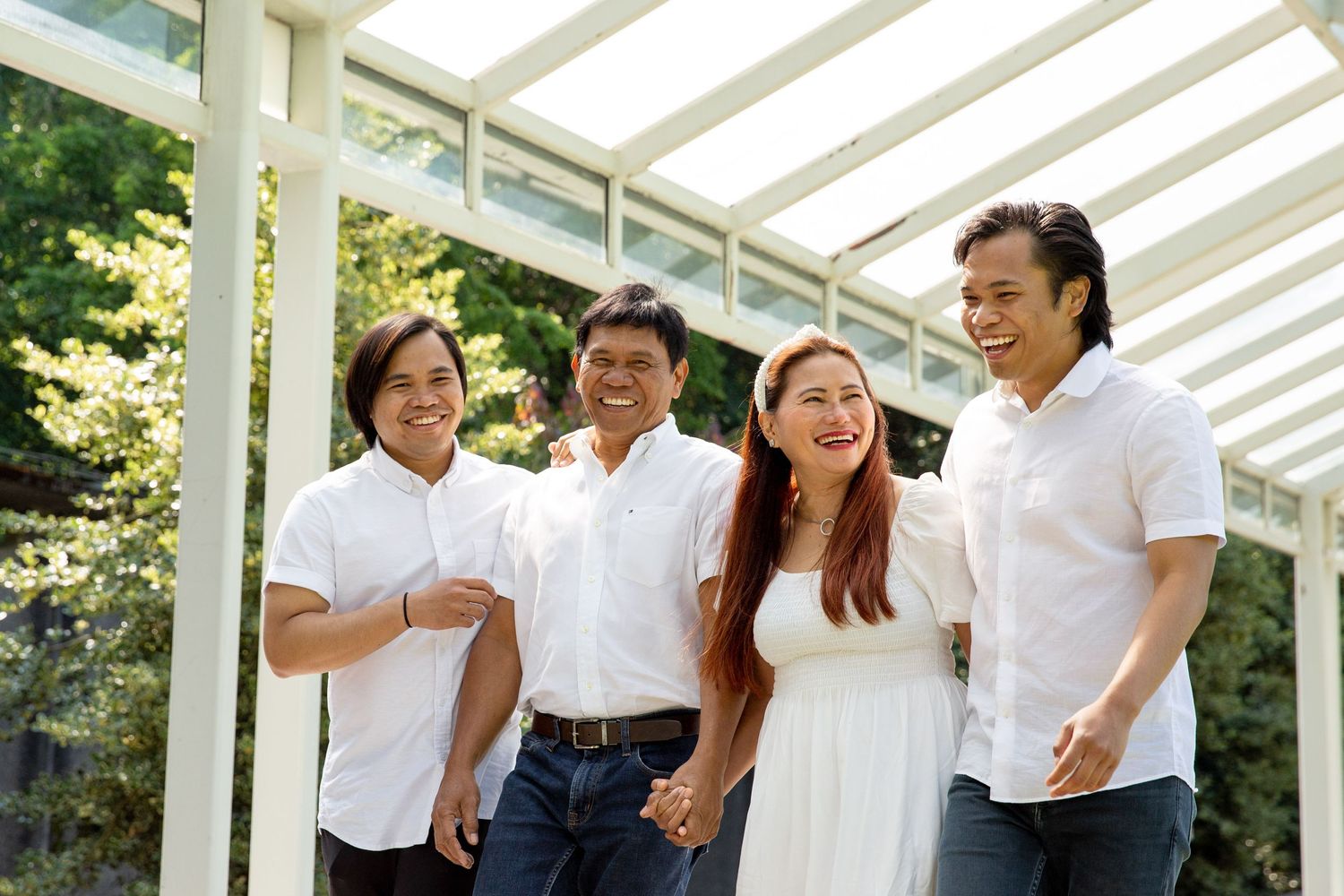 Four people in white shirts pose together under a modern pergola structure.