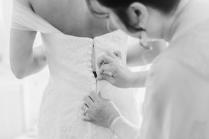 Black and white detail shot of wedding dress being buttoned up.