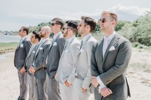 Groomsmen in various shades of grey suits posing together outdoors.