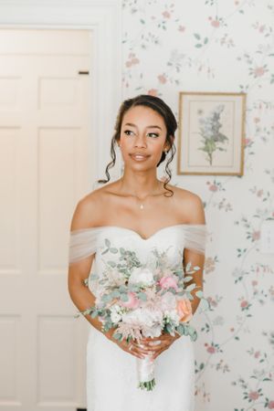 Elegant wedding photography in an interior with floral wallpaper and soft natural lighting.