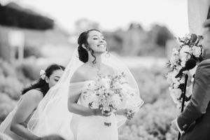 Black and white photo of joyful moment during outdoor wedding ceremony with floral bouquet.
