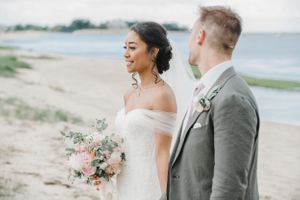 A close-up beach wedding portrait showing a beautiful bouquet of pink and white flowers.