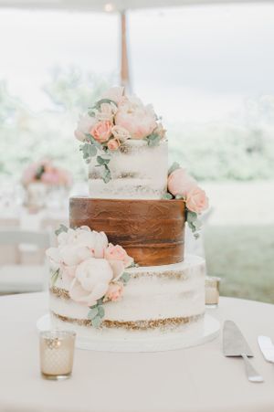 Elegant three-tier wedding cake with blush roses and metallic accents.