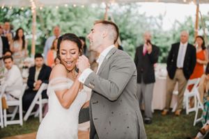 A couple dances together at their wedding reception while guests watch in the background.