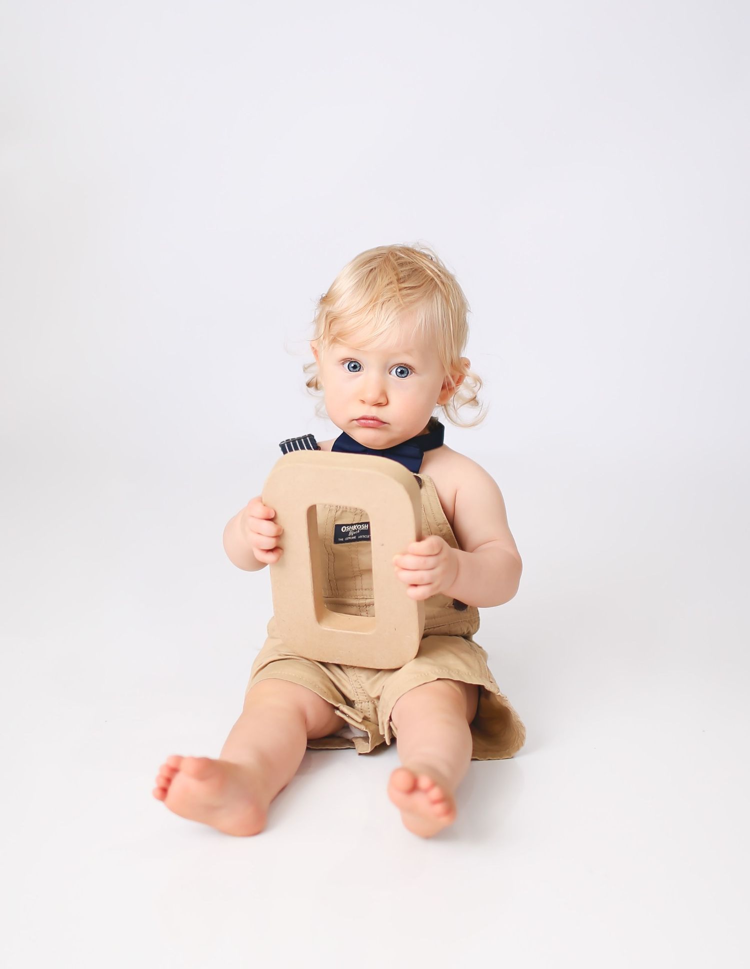 Baby boy holding cardboard letters to spell ONE
