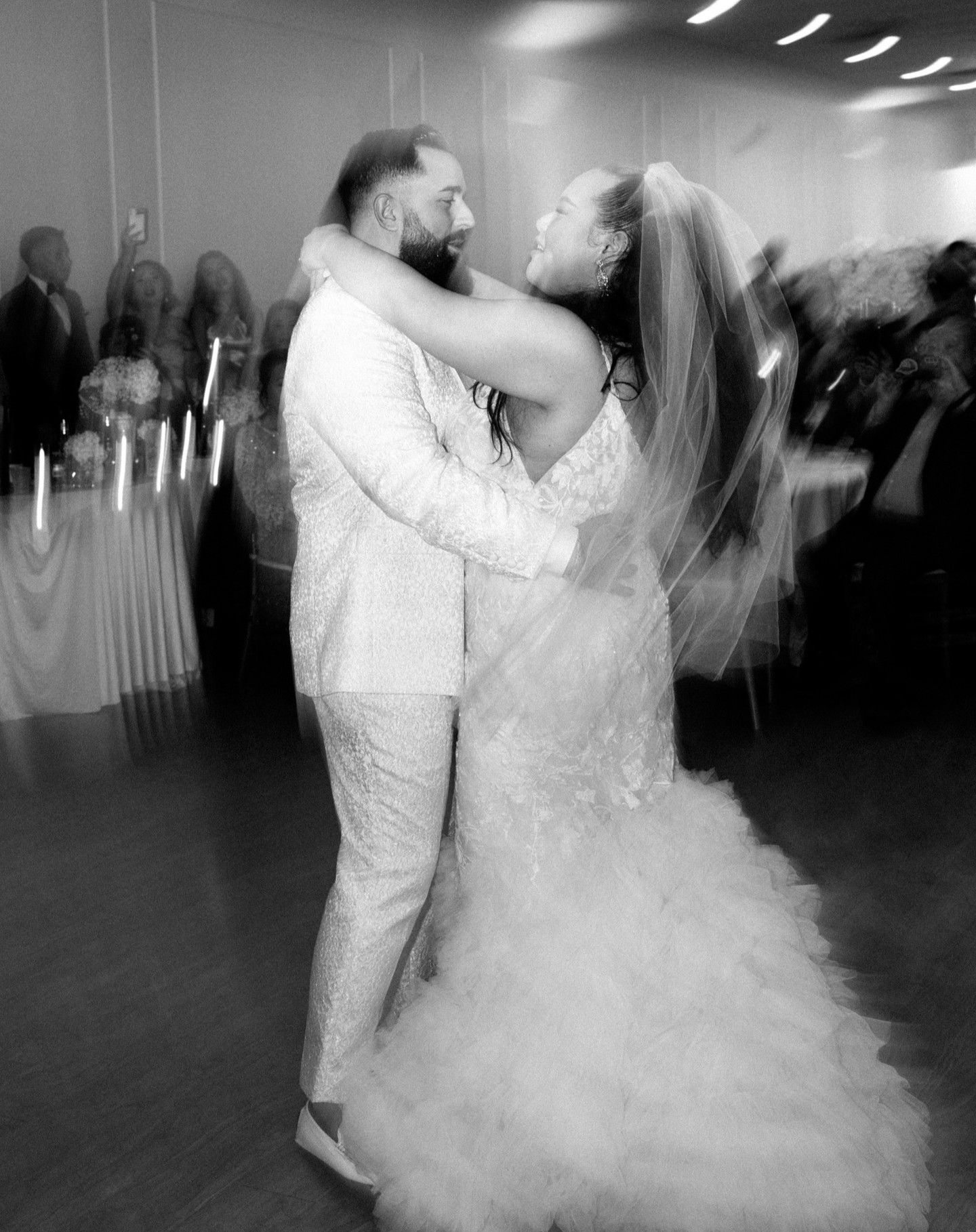 A couple shares their first dance as newlyweds in a dreamy black and white wedding reception photo.