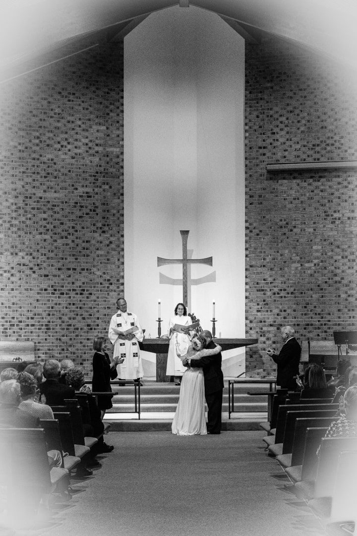 second marriage for bride and groom shown hugging in front of pastor after vows spoken at Puyallup United Methodist Church.