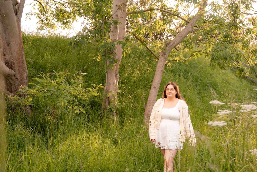 Figure in white lace dress standing among birch trees in lush green setting. Lincolnshire branding photographer.