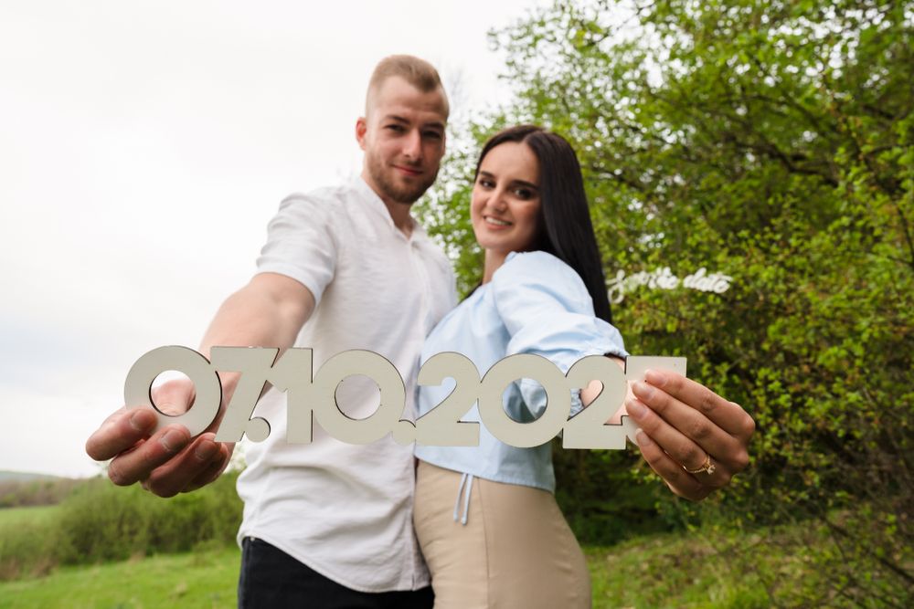 Couple displaying numbers against a natural green background in a romantic outdoor setting.