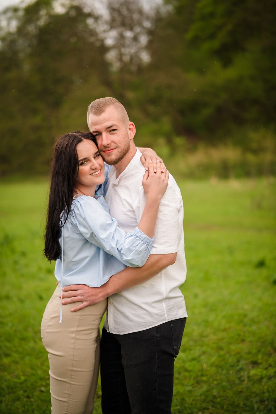 Couple in coordinated white and blue outfits embracing in an outdoor setting.
