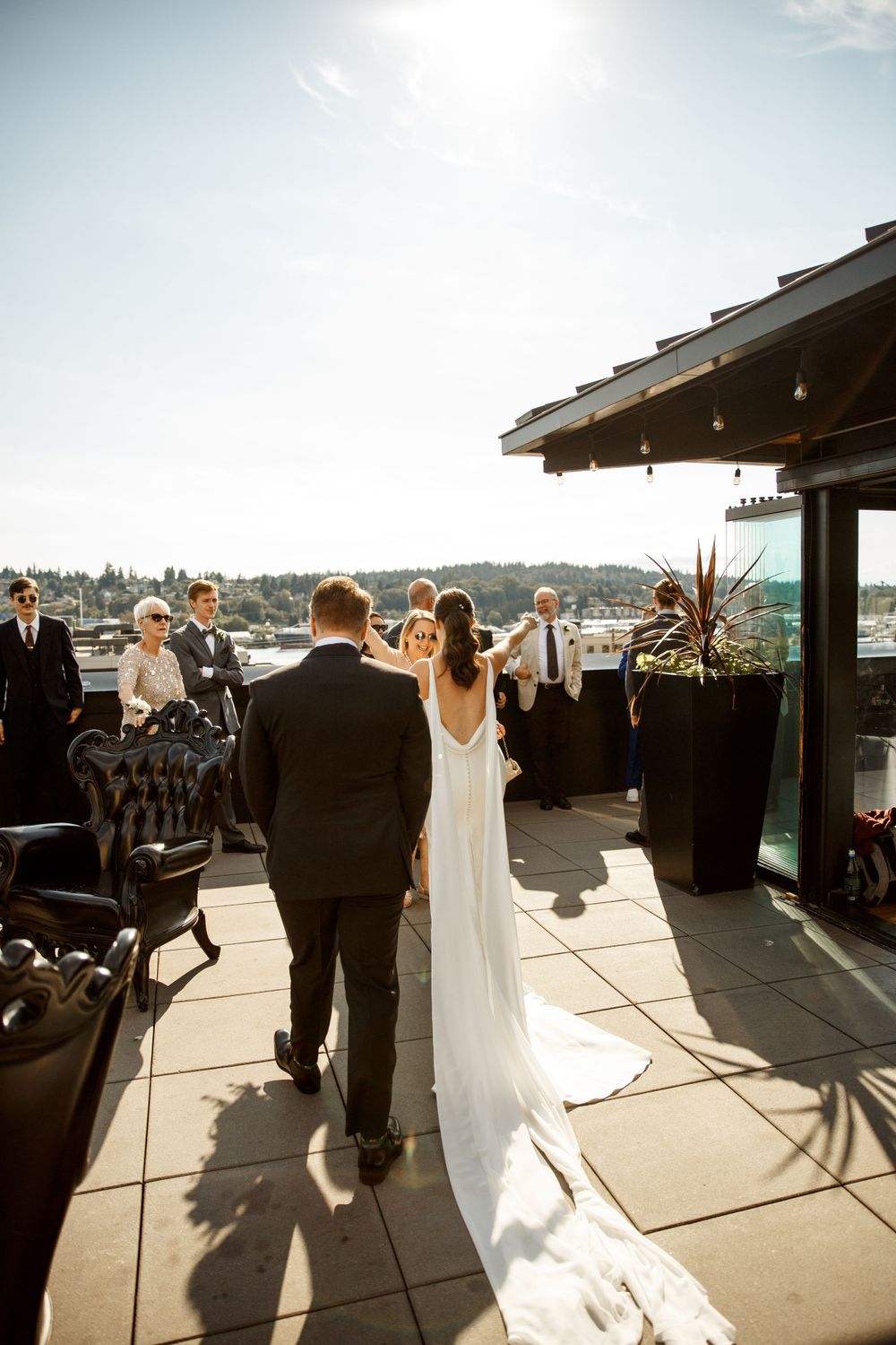 Wedding couple on outdoor terrace venue with waterfront views on sunny day.