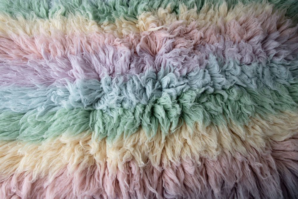 Soft pastel rainbow Mongolian fur rug texture in pink purple green yellow.