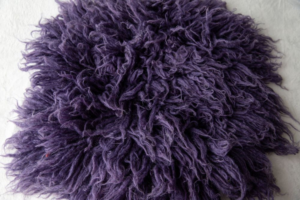 Fluffy purple Mongolian lamb fur rug with curly texture.