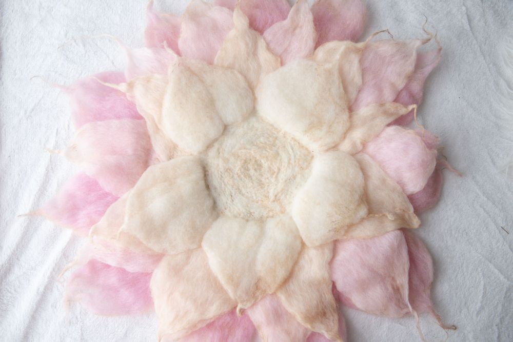 Handmade felted wool flower mat in cream and pink tones.