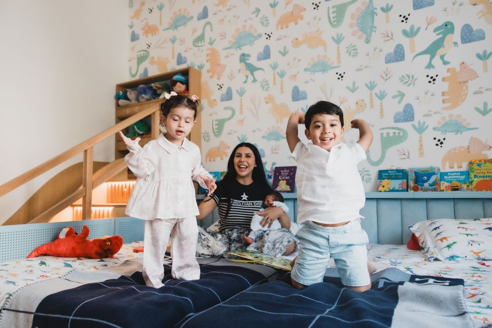 Children jumping with excitement on a bed while reading books together.