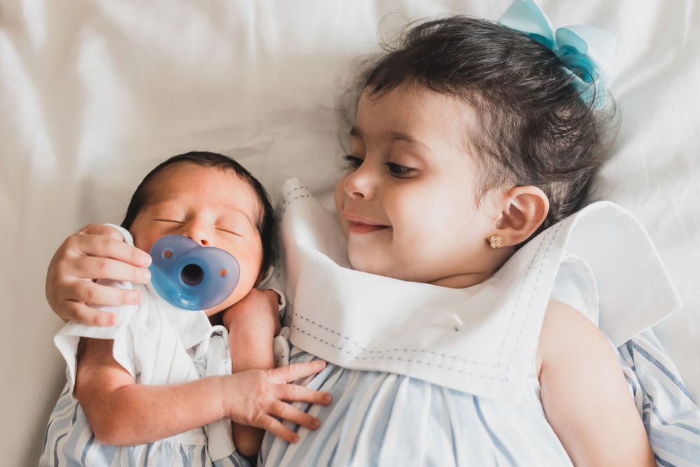 Young siblings sharing a sweet moment together on white bedding.