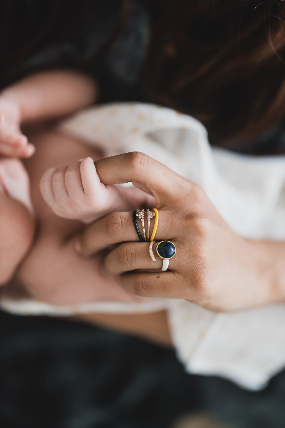 Close-up sequence of hands with delicate gold rings and gemstones showing on fingers captured against a light surface.