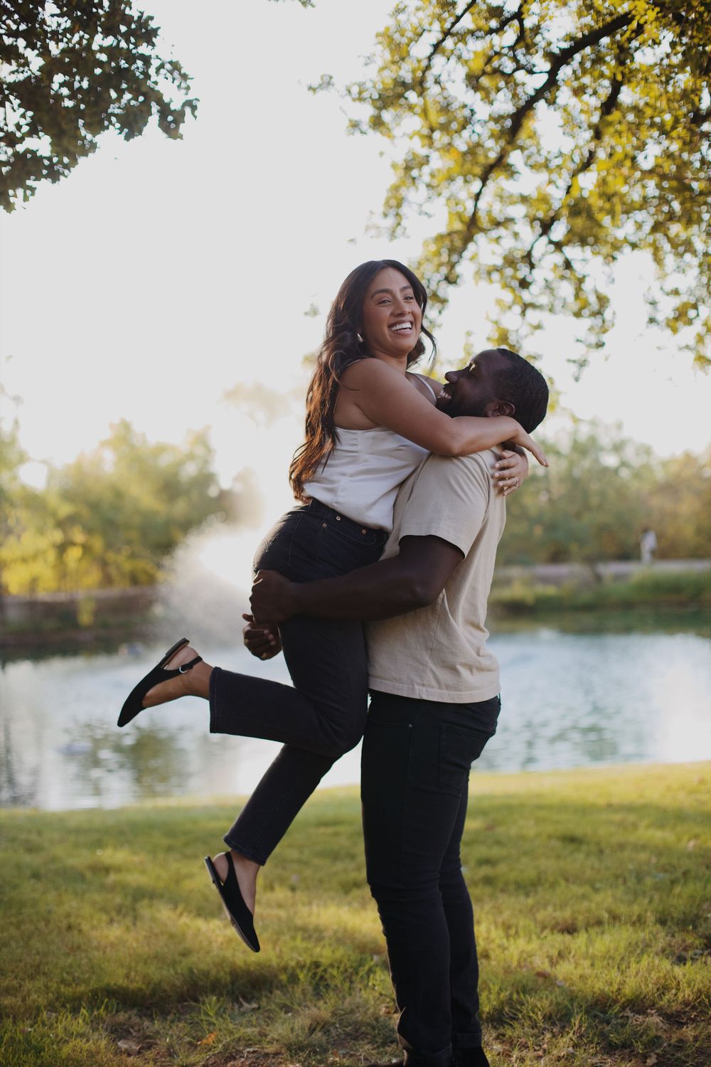 Engaged couple holding each other near the pond.