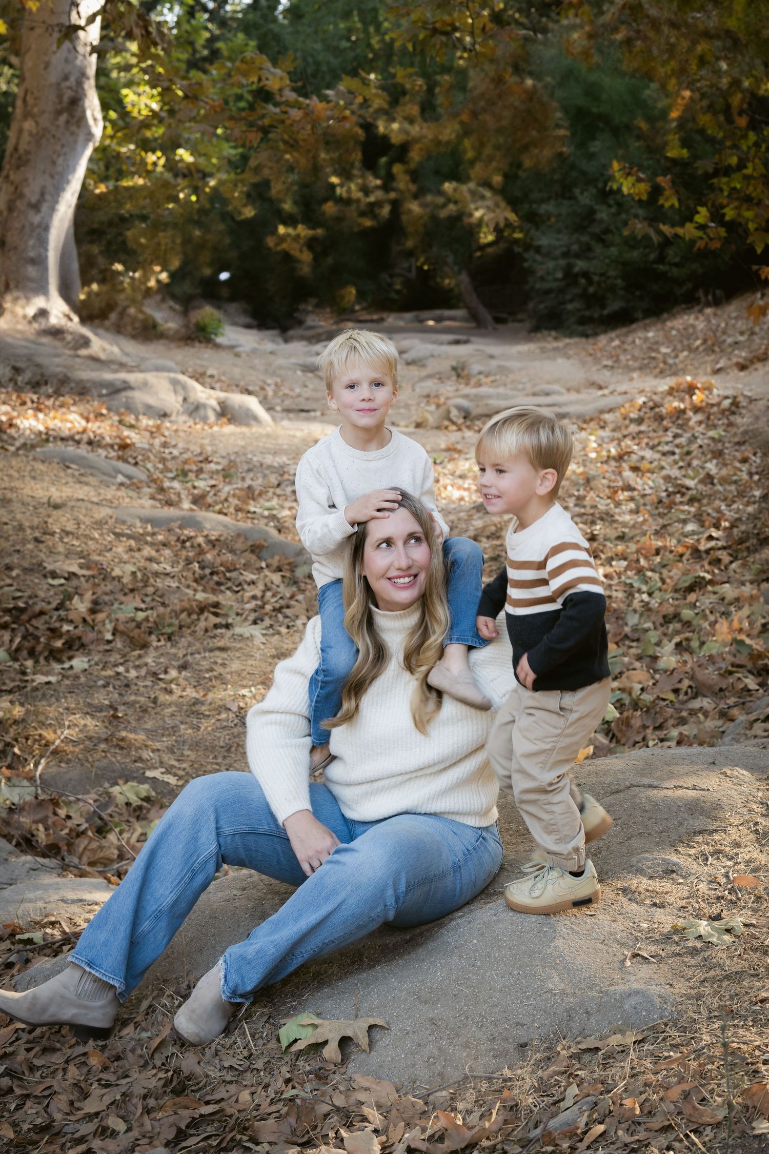 Candid family moments captured on stone steps surrounded by autumn leaves and trees.