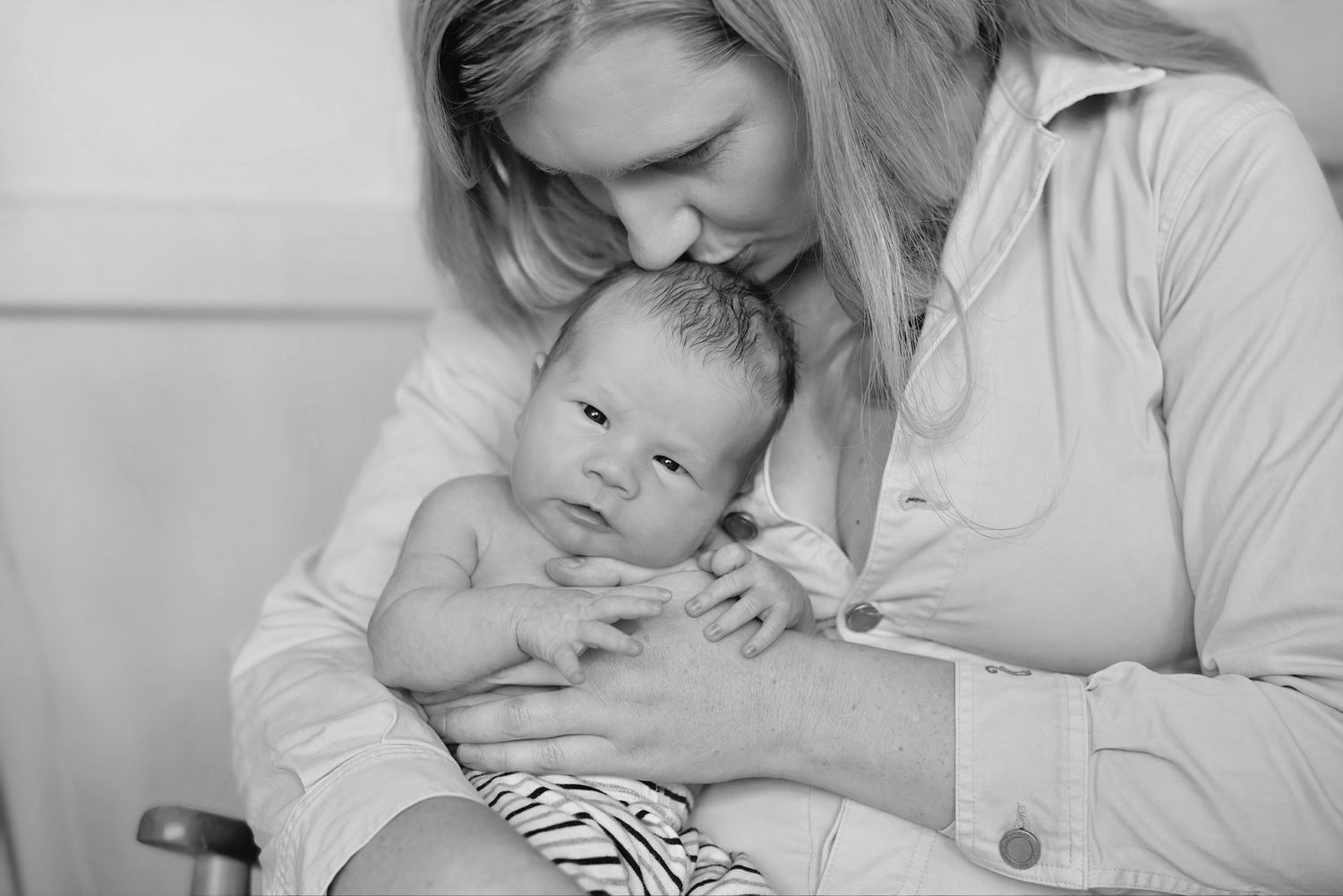 Intimate black and white portrait of parent bonding with newborn baby.