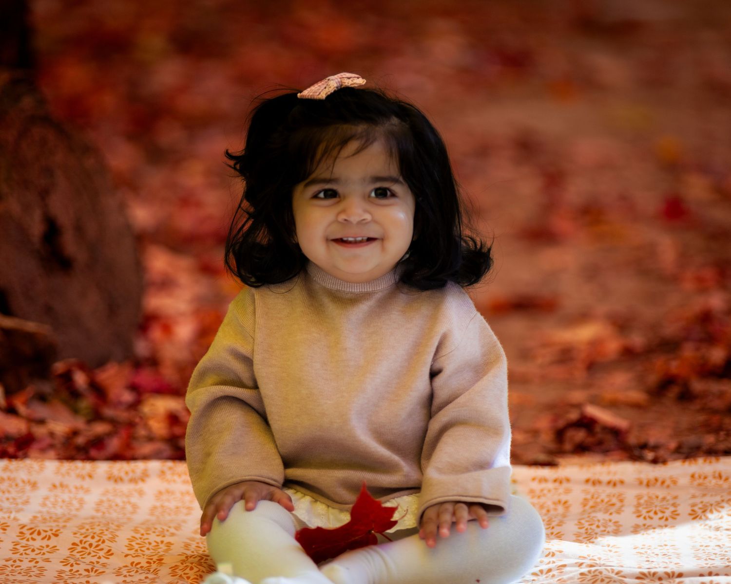 Adorable 1-year-old outdoors, surrounded by vibrant autumn leaves, capturing the essence of a joyful fall moment.