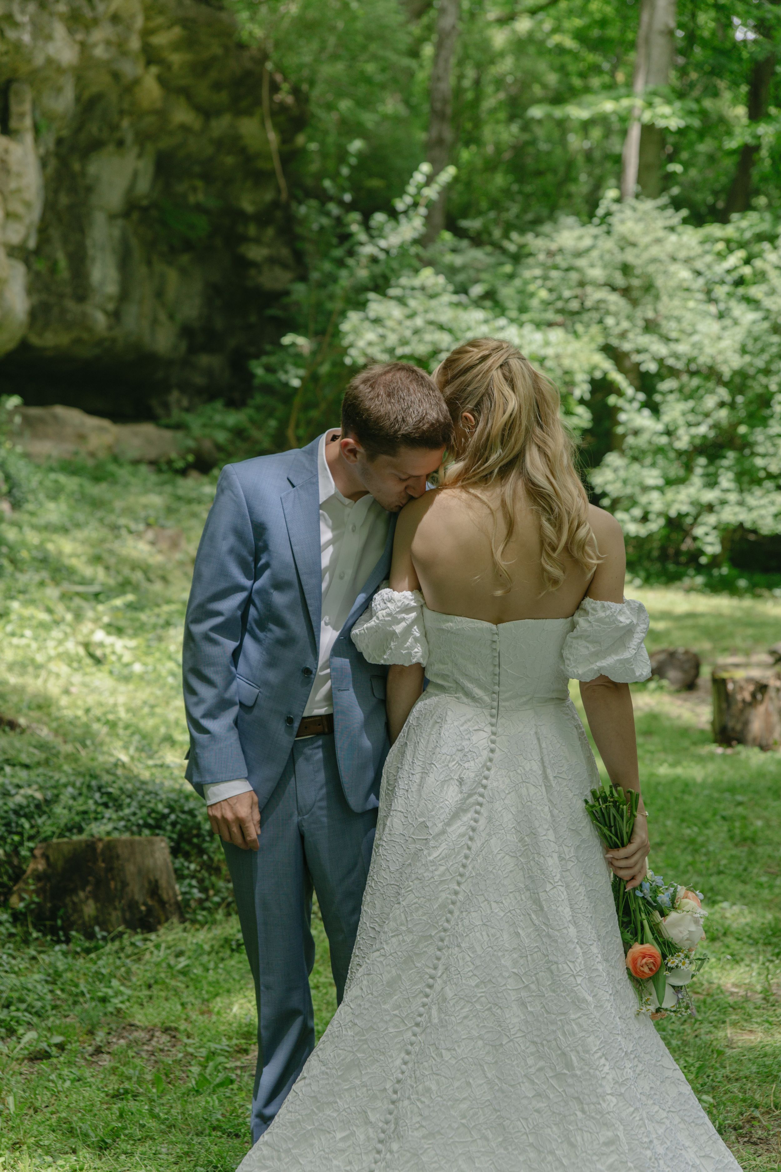 Beautiful wedding dress details photographed in a lush green garden setting.