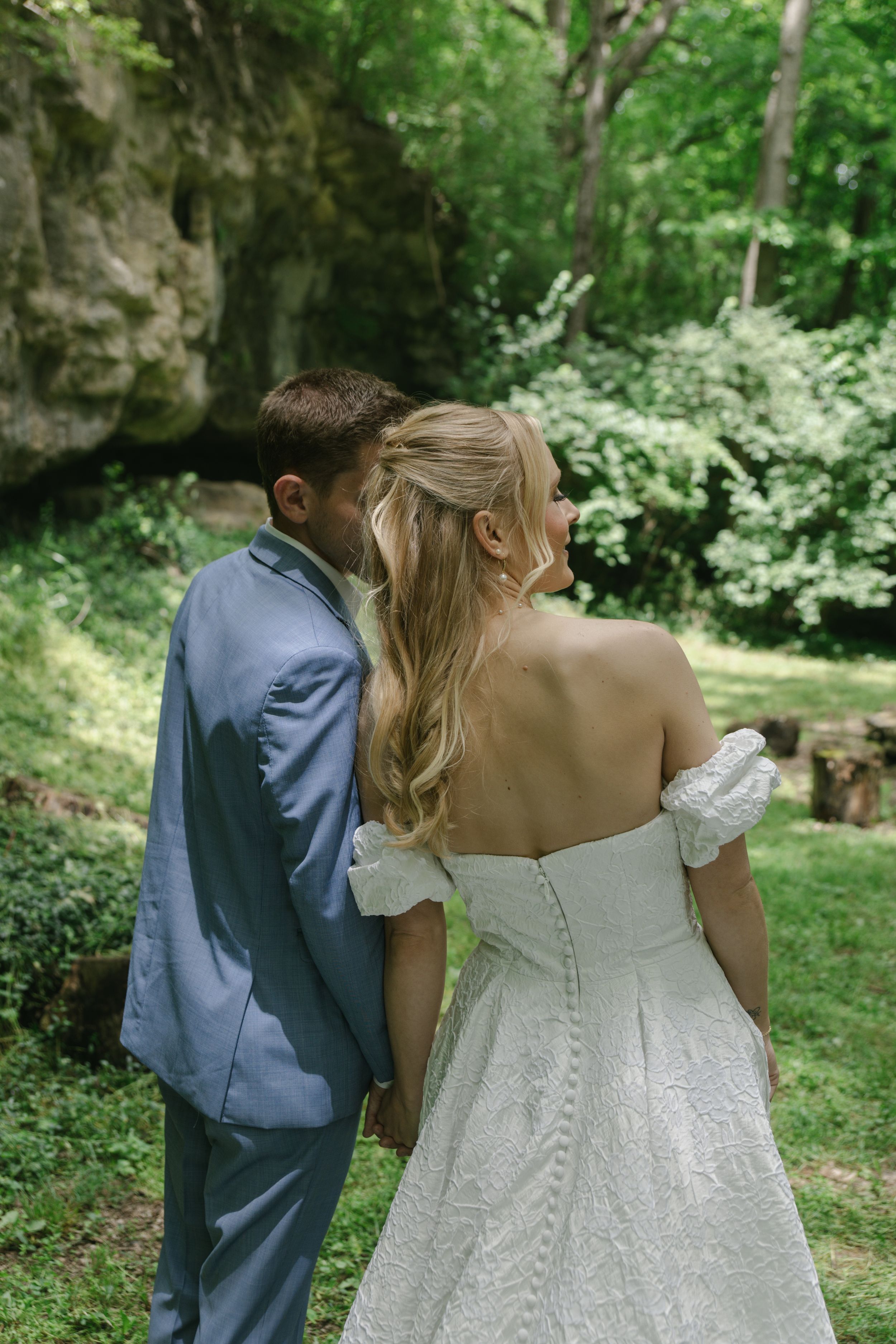 Close-up shots of an ornate white wedding dress with detailed back buttons in a garden setting.