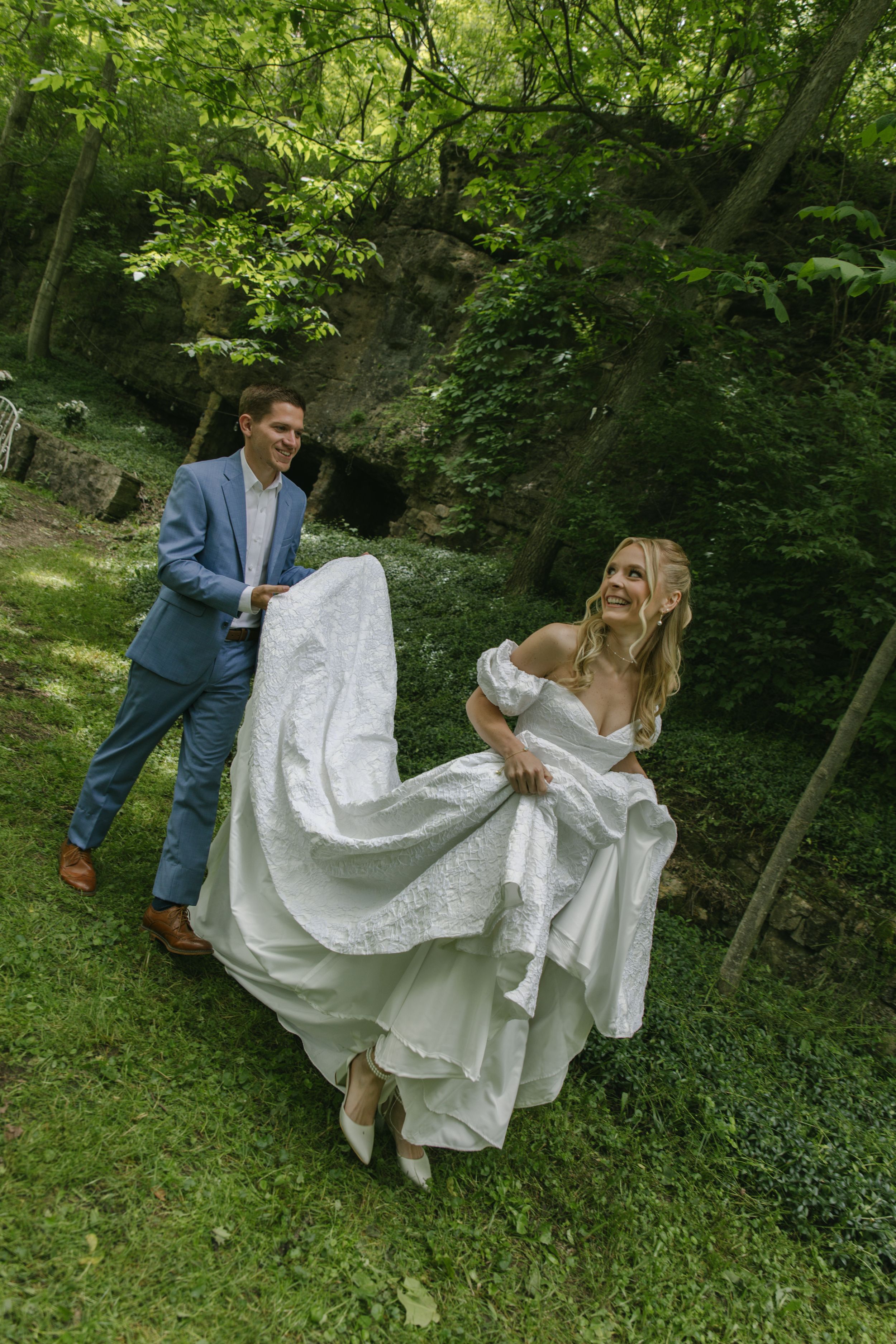 Playful sequence showing a couple arranging a flowing wedding dress in a wooded setting.