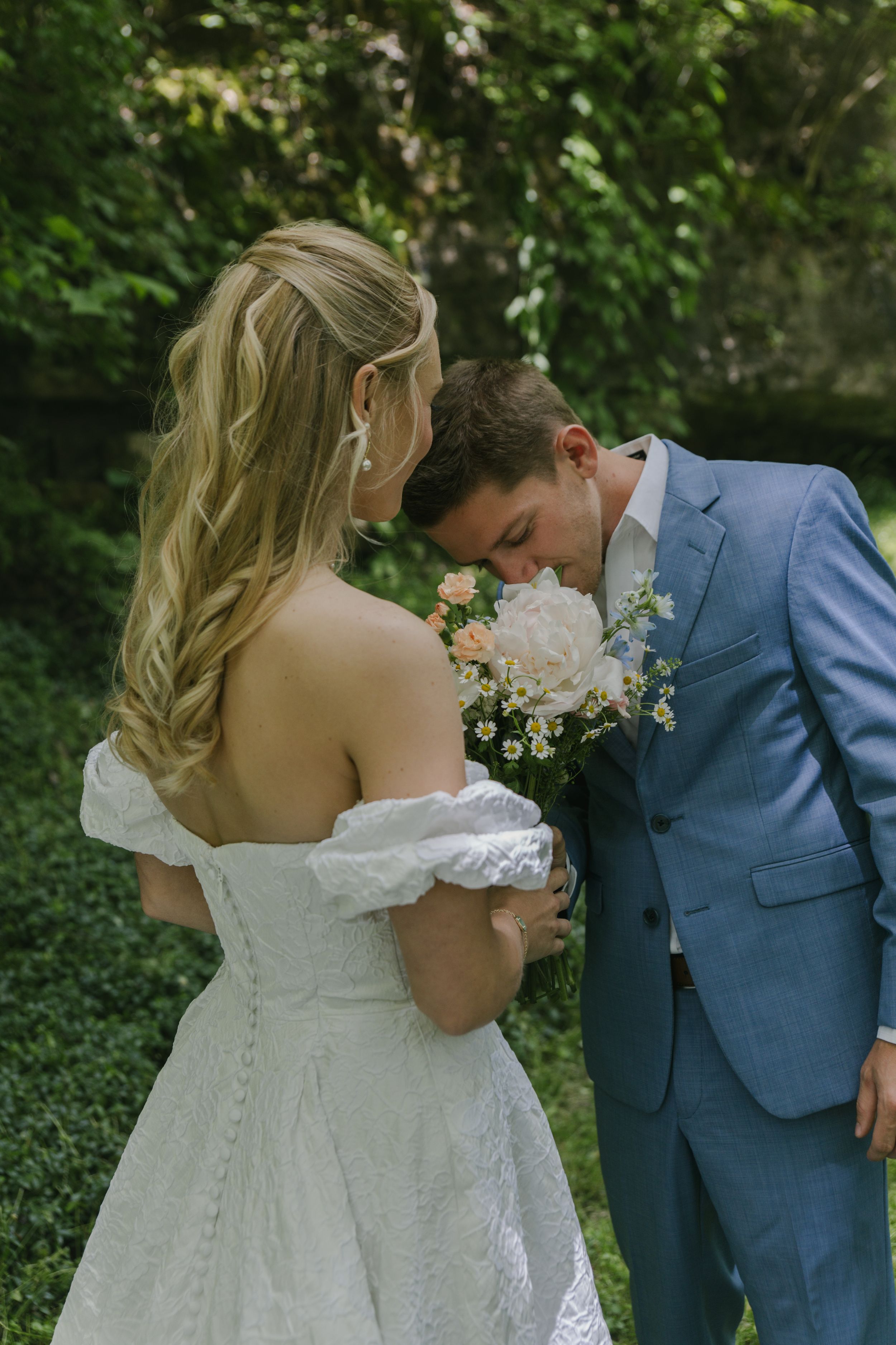 An intimate wedding moment with a bouquet between the couple in a wooded setting.