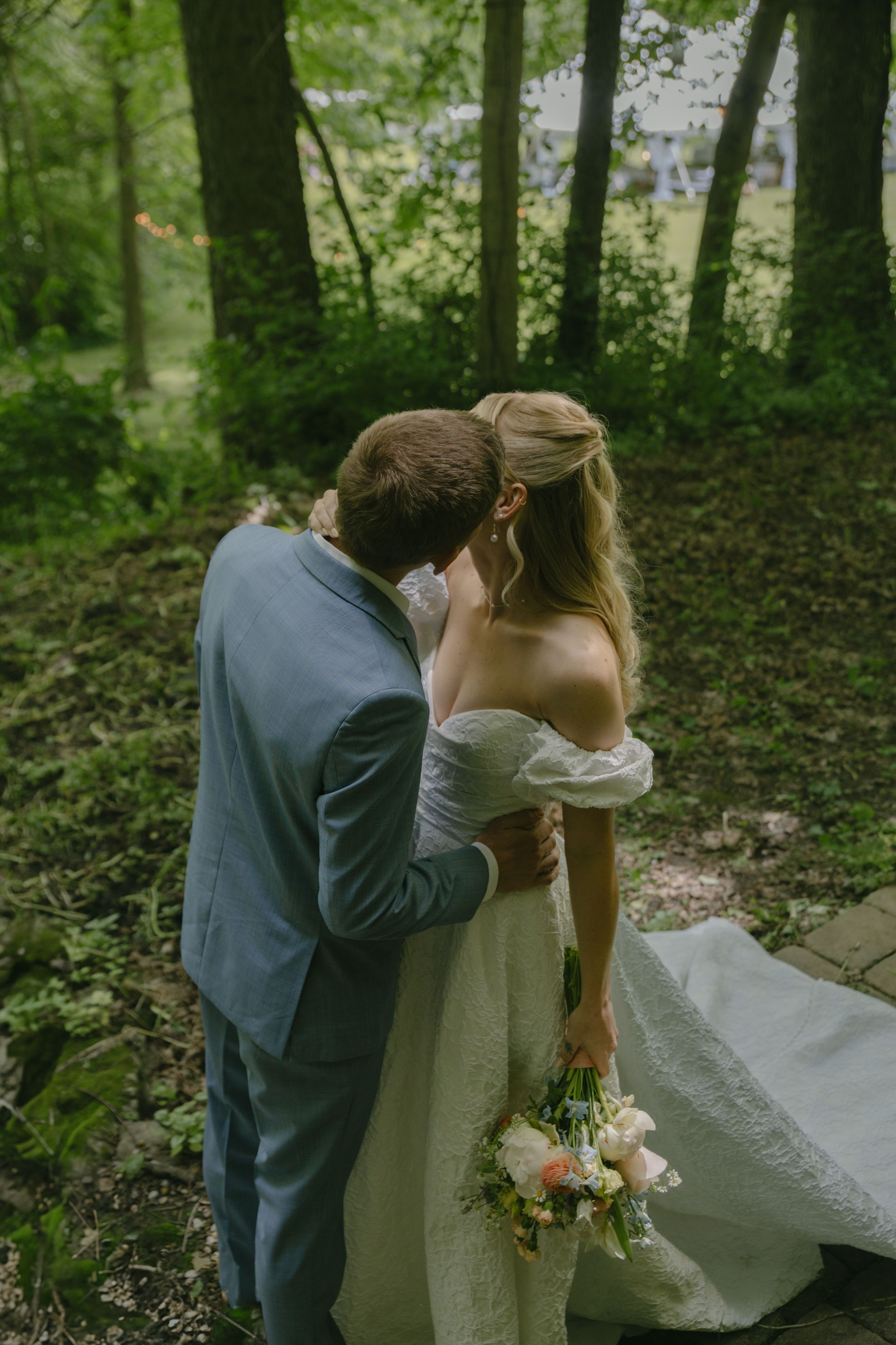 A tender wedding photography moment set against a verdant forest backdrop.