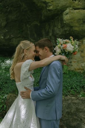 A romantic wedding portrait against a rocky backdrop with soft natural lighting.