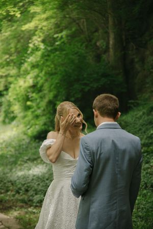 An emotional first look wedding moment captured in a serene forest setting.
