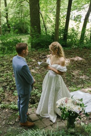 A wedding ceremony moment in a woodland setting with vows being exchanged.