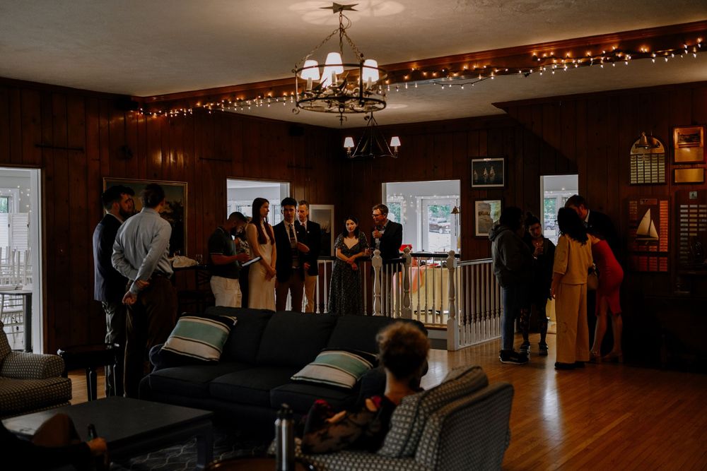 A long wooden dance floor surrounded by string lights and wooden beams in a rustic event venue.