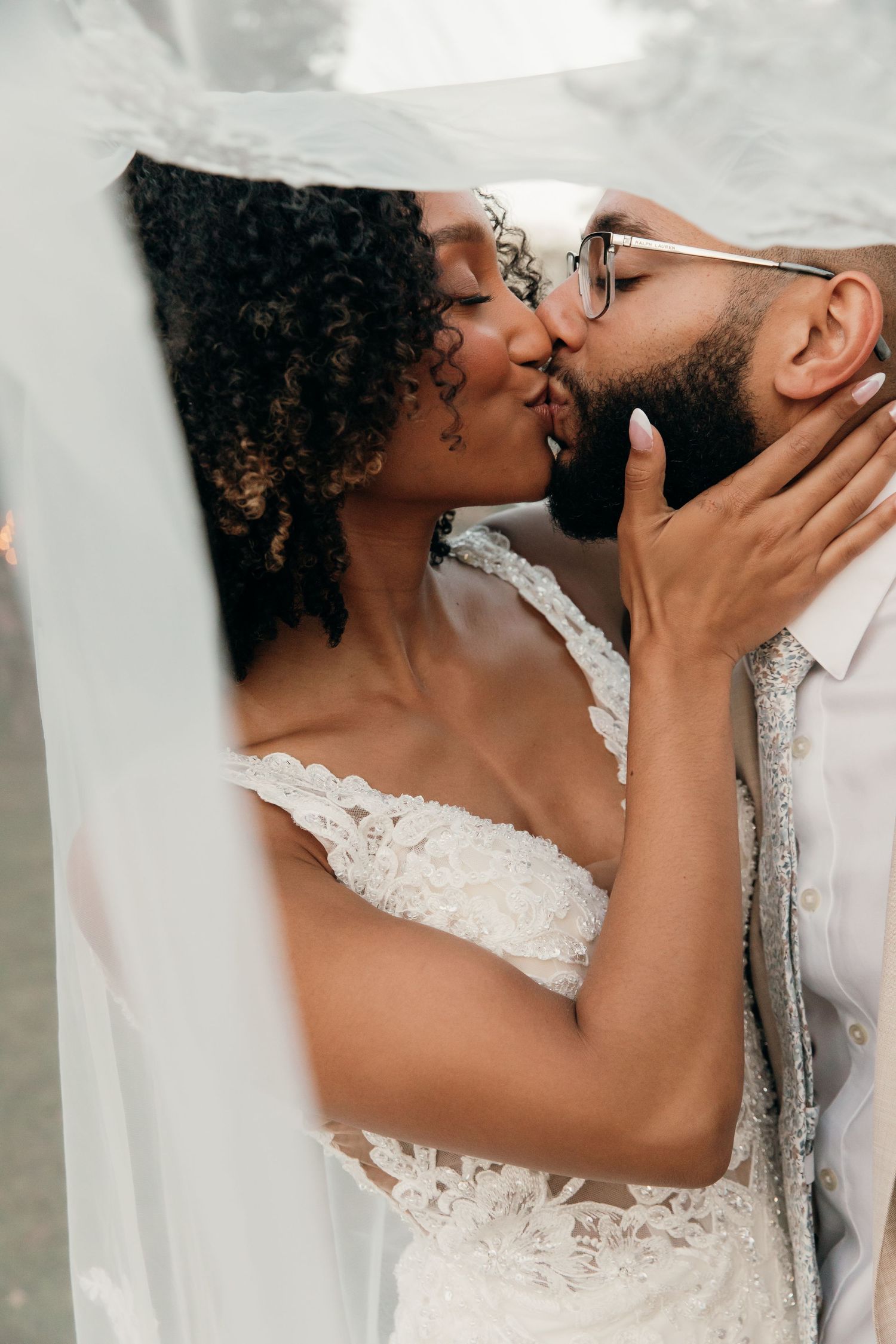 A romantic wedding scene showing an intimate kiss between two people in formal wedding attire.