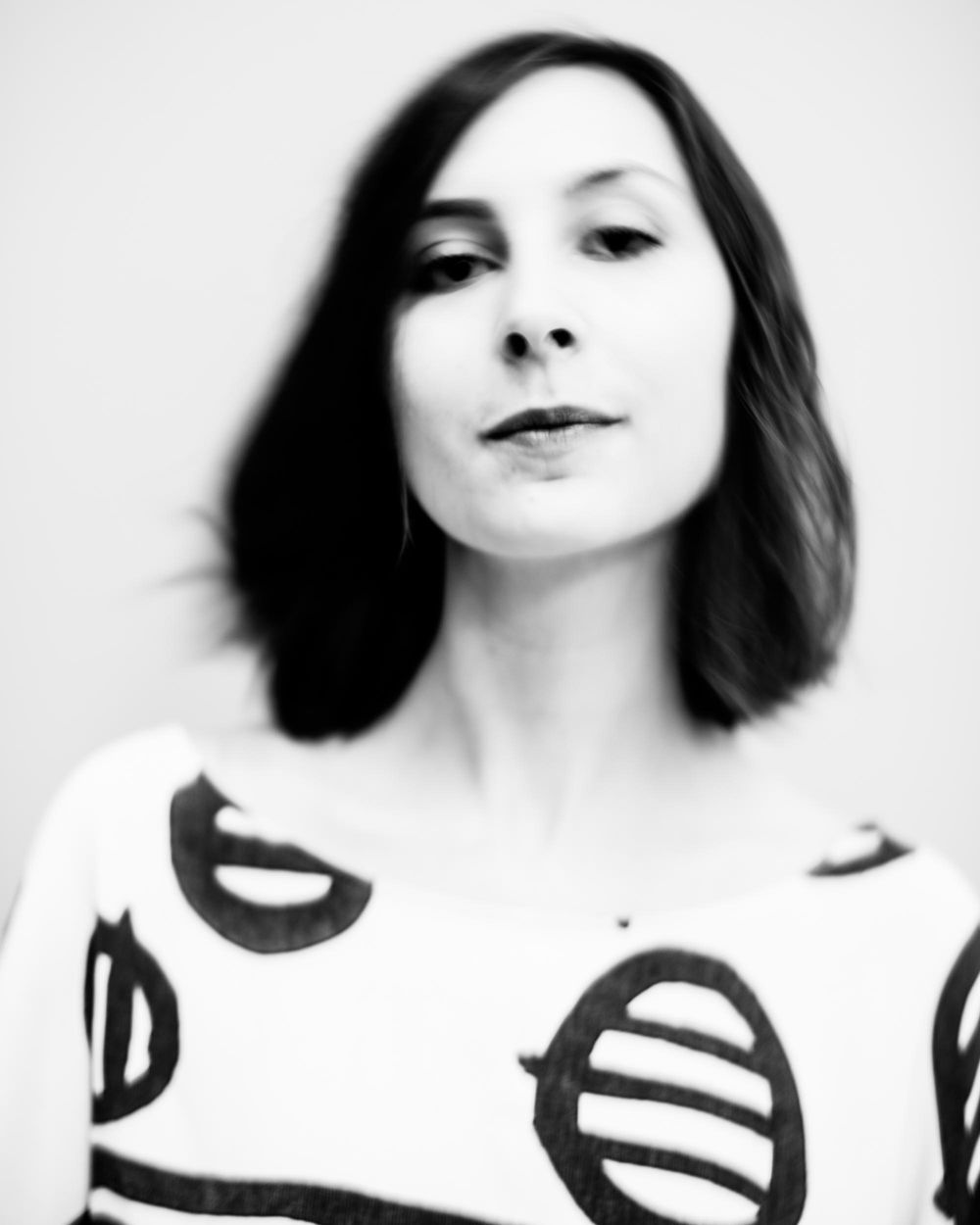 Artistic black and white portrait featuring a person in a white top with bold circular patterns.