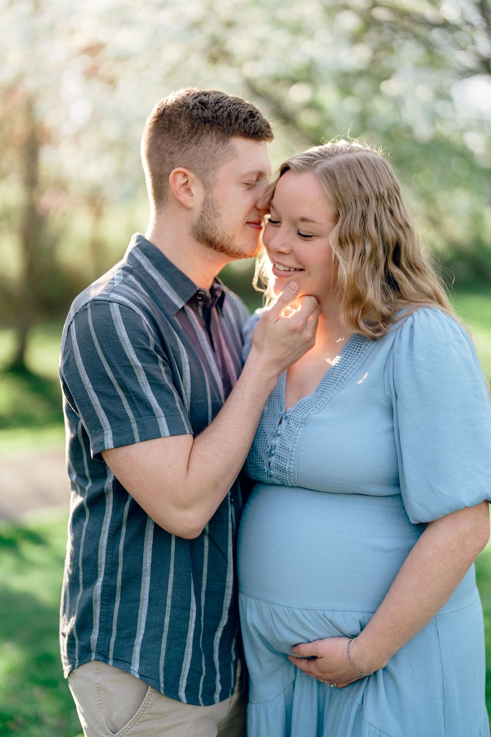 A tender maternity photo shows a couple embracing outdoors, with the woman wearing a flowing blue dress at F.A. Seiberling Nature Realm Ohio