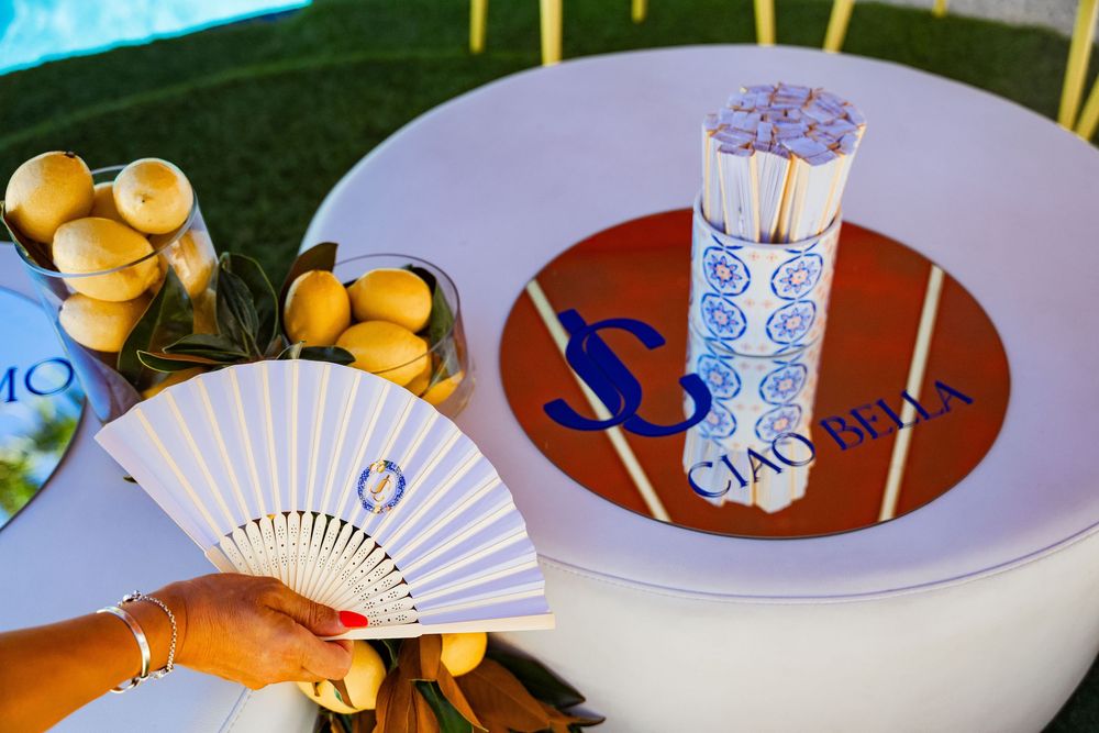 An elegant table setting with white fan decorations, blue accents, and sweet treats arranged on white plates.