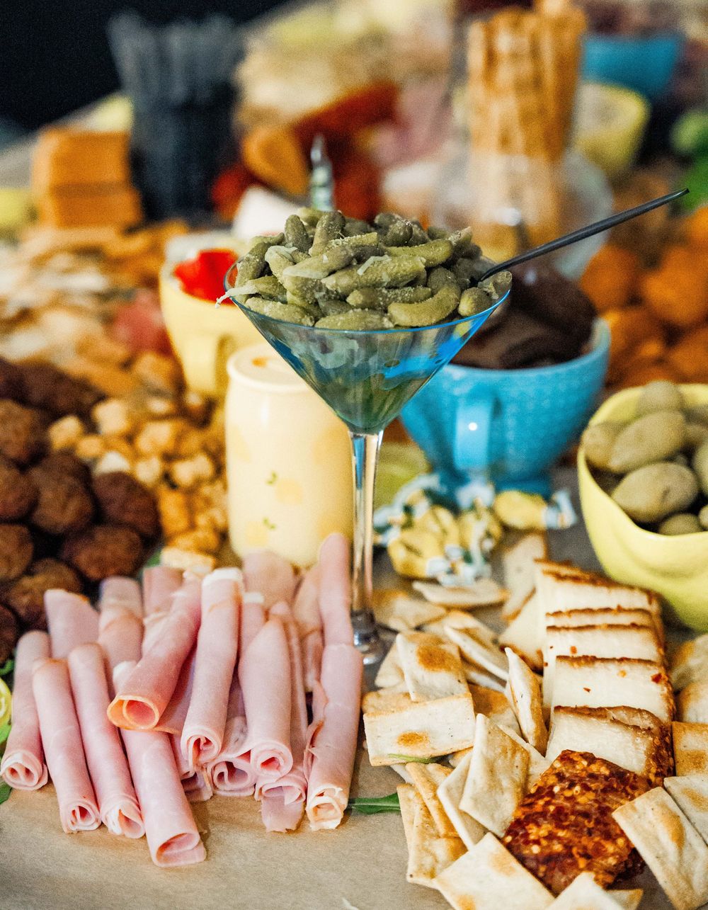 A decorative charcuterie board spread with rolled meats, cheese, crackers, olives, and nuts arranged in an appetizing pattern.