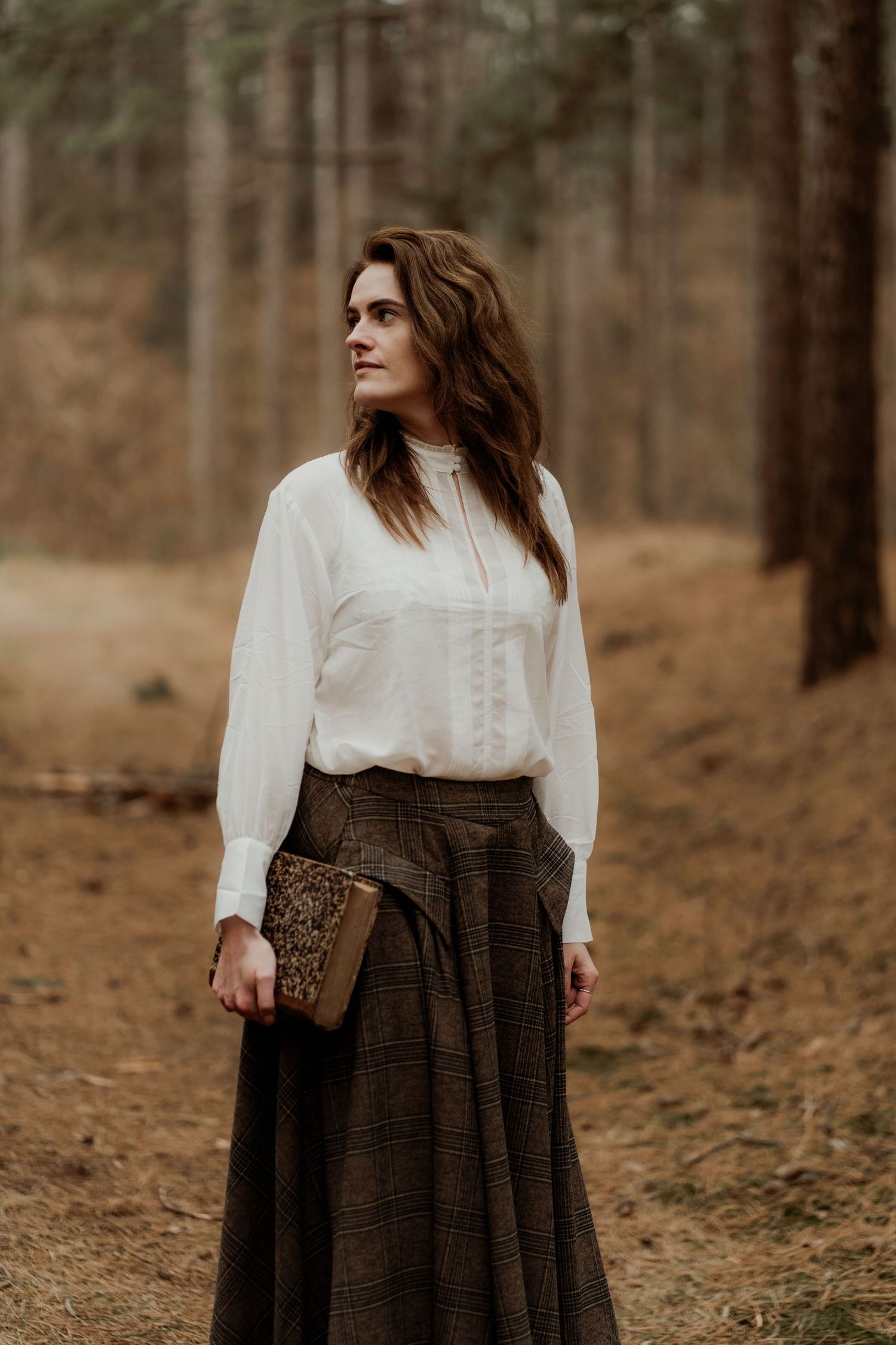 A vintage-inspired outfit featuring a white Victorian blouse and brown maxi skirt in an autumn forest setting.