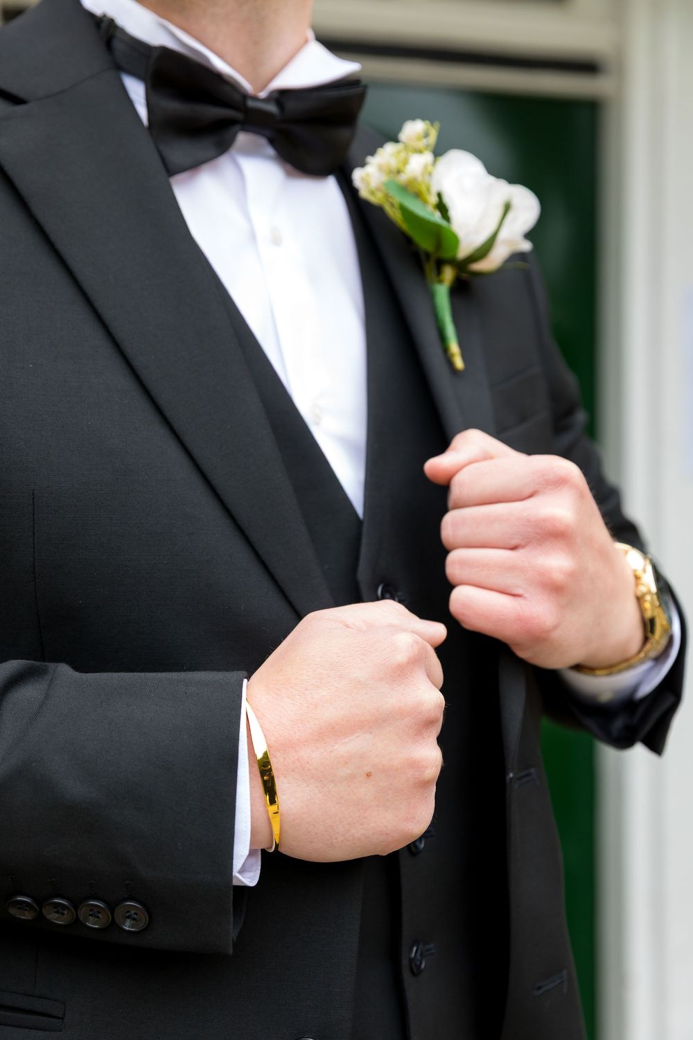 Close-up of the groom’s tuxedo, boutonnière, and wrist accessories outside the venue.